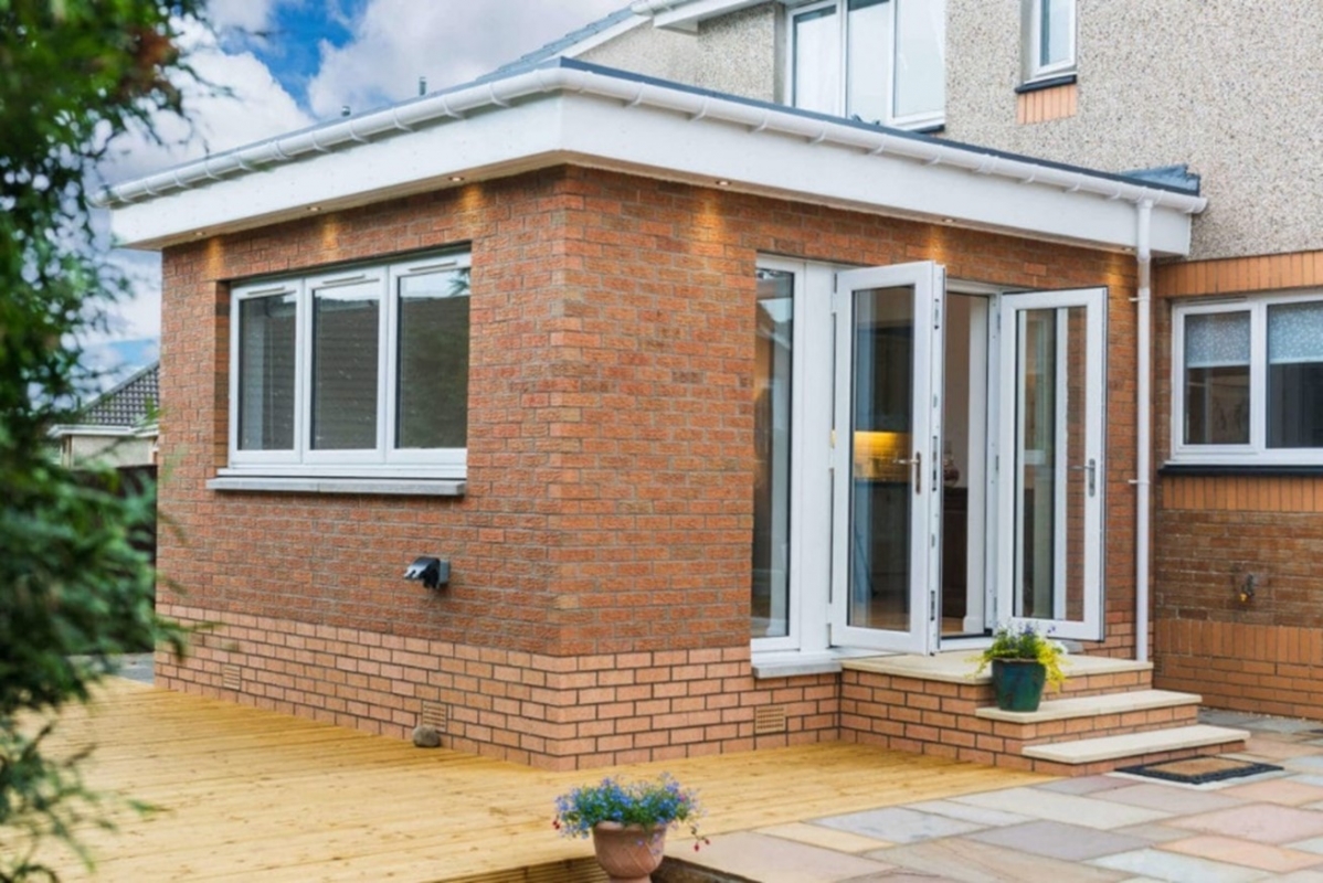 Traditional brick and flat roof house extension with window and patio door